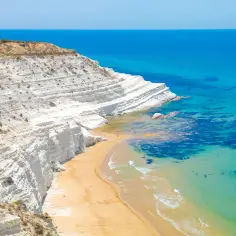 Białe klify i złota plaża nad turkusowym morzem. To miejsce to jedna z najpiękniejszych plaż Sycylii, idealna na wakacje.