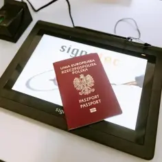 Polski paszport na ekranie tabletu. Urządzenie do skanowania odcisków palców obok. Tak sprawdzisz numer paszportu.