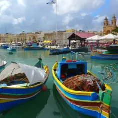 Kolorowe łodzie rybackie w Marsaxlokk, Malta. Ceny pamiątek i jedzenia mogą być różne, ale widok jest bezcenny.