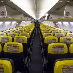 Wnętrze samolotu Ryanair z rzędami żółtych zagłówków. Trudno określić, ile jest miejsc w samolocie Ryanair, ale ten widok sugeruje, że jest ich bardzo dużo.