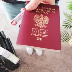 Paszport w dłoni, obok dowód osobisty i walizka. Czy do Rumunii potrzebny jest paszport? Tak, jeśli nie jesteś obywatelem UE.