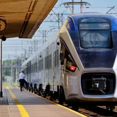 Na dworcu stoi nowoczesny pociąg Intercity. Czy można jechać wcześniejszym pociągiem? Zegar na peronie pokazuje czas.