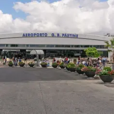 Ludzie z bagażami czekają przed wejściem do Aeroportu G. B. Pastine, Rzym Ciampino.