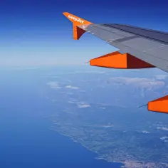 Widok z okna samolotu easyJet na wybrzeże i góry. Bagaż podręczny zmieści się idealnie.