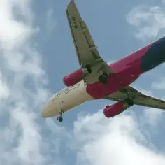 Samolot Wizzair z różowymi silnikami leci na tle chmur. Zastanawiasz się, wizzair ile można przewieźć alkoholu?