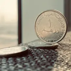 Monety z napisem "United Arab Emirates" - waluta w Dubaju. Jedna z nich stoi pionowo, ukazując cyfrę 1.