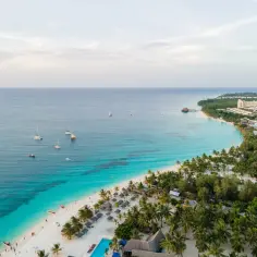 Rajska plaża na Zanzibarze z turkusową wodą, palmami i łodziami. Sprawdź atrakcyjne zanzibar ceny na wakacje marzeń!