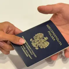 Dłoń przekazuje paszport. Dowiedz się, jak odebrać paszport, aby rozpocząć podróż.