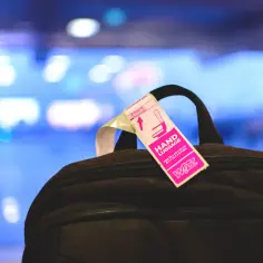 Różowa etykieta "HAND LUGGAGE" Wizz Air na czarnym plecaku.