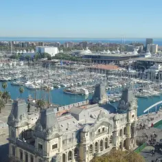 Widok na port pełen jachtów i statków, z charakterystycznym budynkiem w stylu barokowym na pierwszym planie. Tak właśnie wygląda Barcelona.