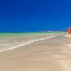 Piękna plaża w Tunezji, idealna na wrzesień. Trzy kolorowe deski windsurfingowe czekają na wiatr.