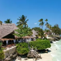 Zanzibar: plaża z palmami i strzechą, turkusowa woda. Nawet po porze deszczowej słońce świeci.