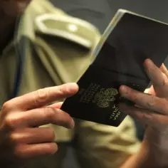 Sprawdzanie numeru paszportu ukraińskiego. Dłoń trzyma otwarta książeczkę paszportu z widocznym godłem.