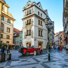 Uliczka w Pradze z czerwonym kabrioletem i zabytkowymi kamienicami. Złota uliczka Praga zachwyca.