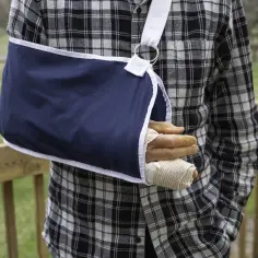 Mężczyzna w kratę z ręką w temblaku. Uraz ręki, który może być objęty ubezpieczenie kl.