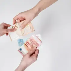 Dwie dłonie przekazują sobie banknoty euro. To popularna waluta austrii, używana do codziennych transakcji.