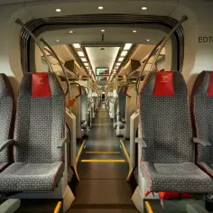 Wnętrze nowoczesnego pociągu PKP Intercity. Siedzenia w szare wzory z czerwonymi zagłówkami. ED78-022.