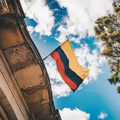 Flaga Kolumbii powiewa na tle błękitnego nieba z chmurami. Czy w Kolumbii jest bezpiecznie? To pytanie zadaje sobie wielu podróżnych.