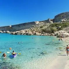 Malta plaże: turkusowa woda, skaliste klify i plażowicze cieszący się słońcem. Kajaki na płytkiej wodzie.