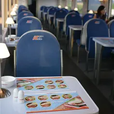 Wnętrze wagonu restauracyjnego PKP Intercity. Stoliki z menu, lampki i wygodne siedzenia. Czy w Intercity jest wars? Tak, można tu zjeść posiłek.