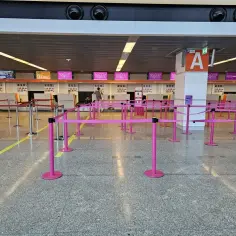 Puste stanowiska Wizzair do odprawy, gotowe na podróżnych. Różowe taśmy wyznaczają kolejki.