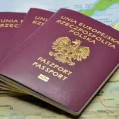 Trzy polskie paszporty leżą na mapie. Dowiedz się, jak wyrobić paszport, by móc podróżować po świecie.