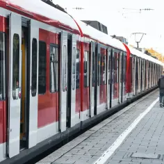Czerwono-biały pociąg PKP z otwartymi drzwiami na peronie, ludzie czekają.