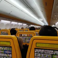 Widok wnętrza samolotu Ryanair z żółtymi siedzeniami i instrukcjami bezpieczeństwa.