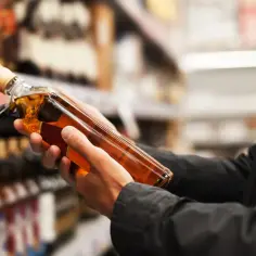Ręce trzymają butelkę whisky, zastanawiając się, ile alkoholu można przewieźć do USA.