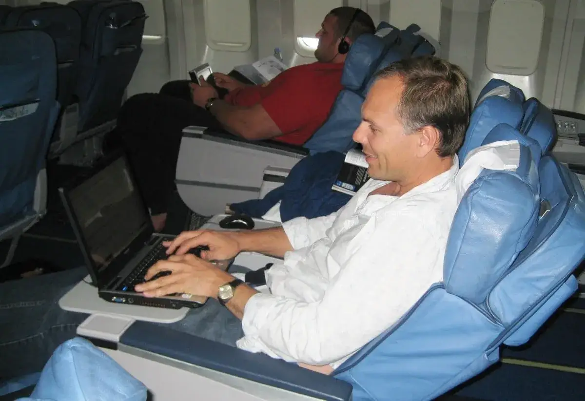 Mężczyzna w samolocie pracuje na laptopie. Czy w samolocie jest wifi? Nie wiadomo, ale wygląda na to, że jest gotów do pracy.