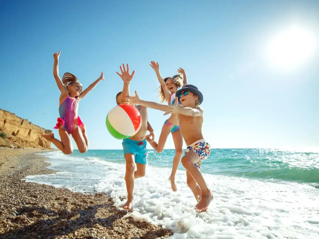 Szczęśliwe dzieci skaczą w falach, idealne miejsce, gdzie na wakacje z dziećmi. Słońce, plaża i zabawa!