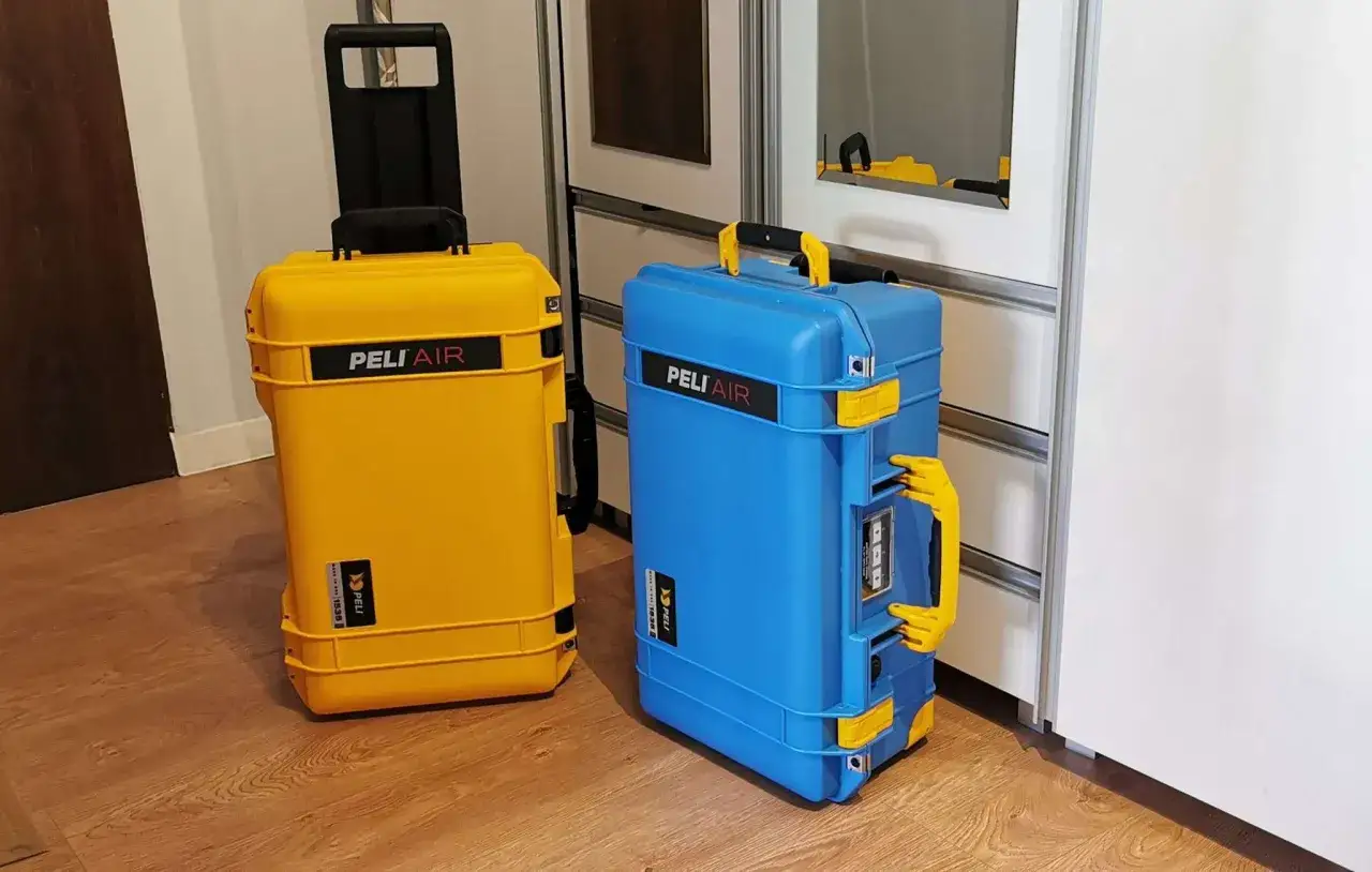 Dwie walizki Peli Air, żółta i niebieska, stoją obok siebie. Wykonane z polipropylenu, są gotowe na każdą podróż.