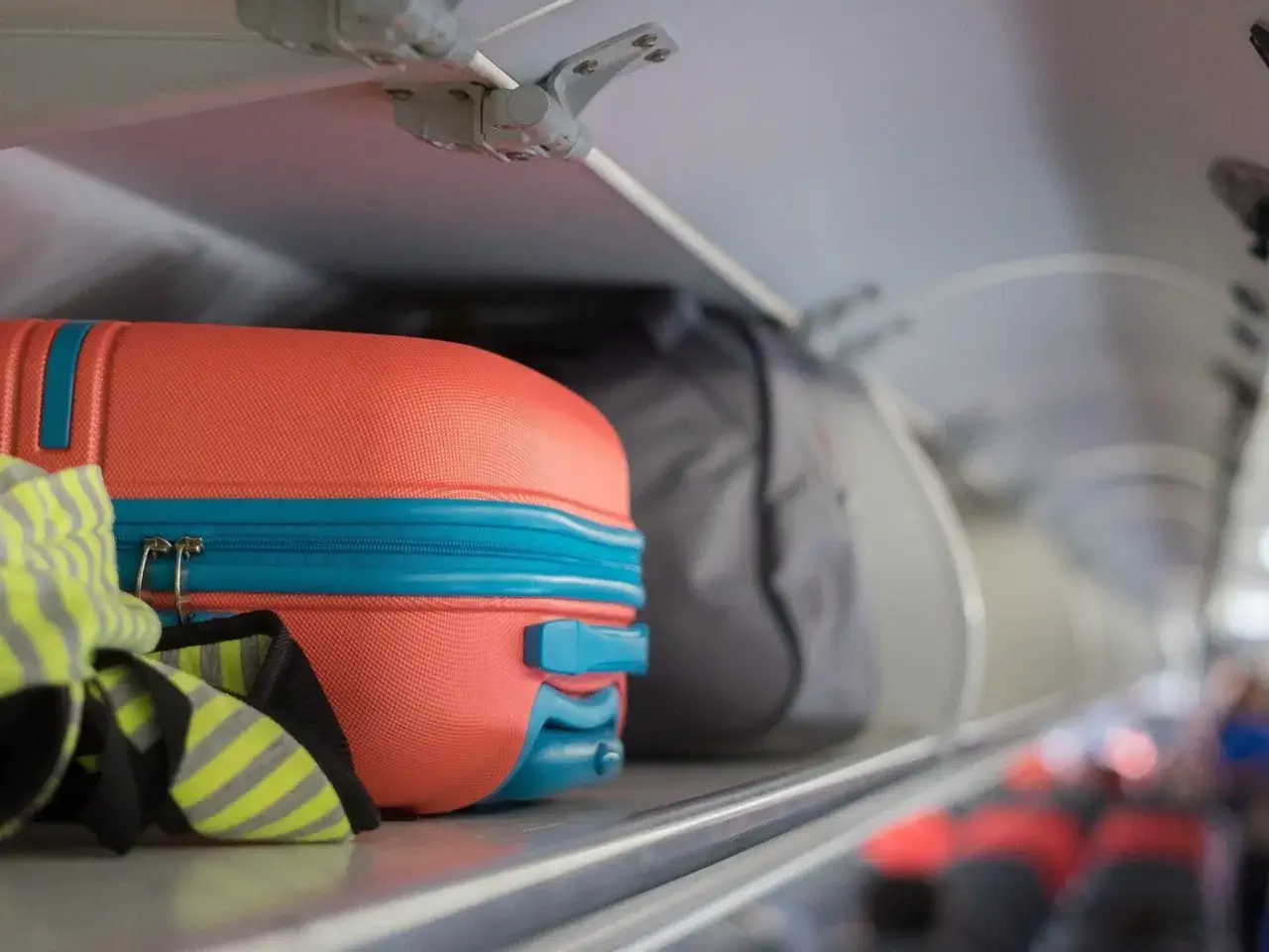 Pomarańczowa walizka i szara torba podróżna w schowku bagażowym samolotu Pegasus Airlines.
