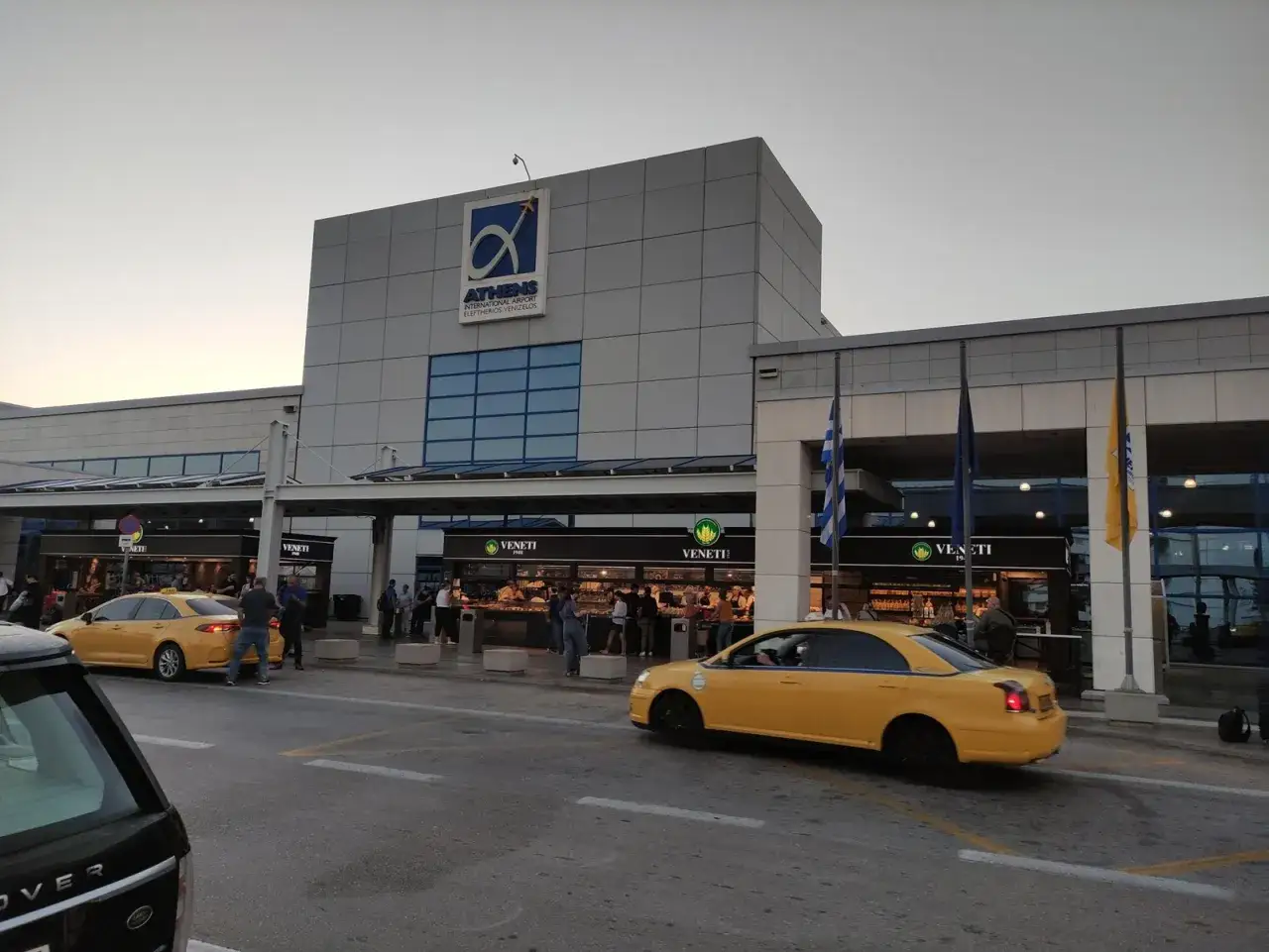 Żółte taksówki czekają na pasażerów przed budynkiem lotniska Ateny.