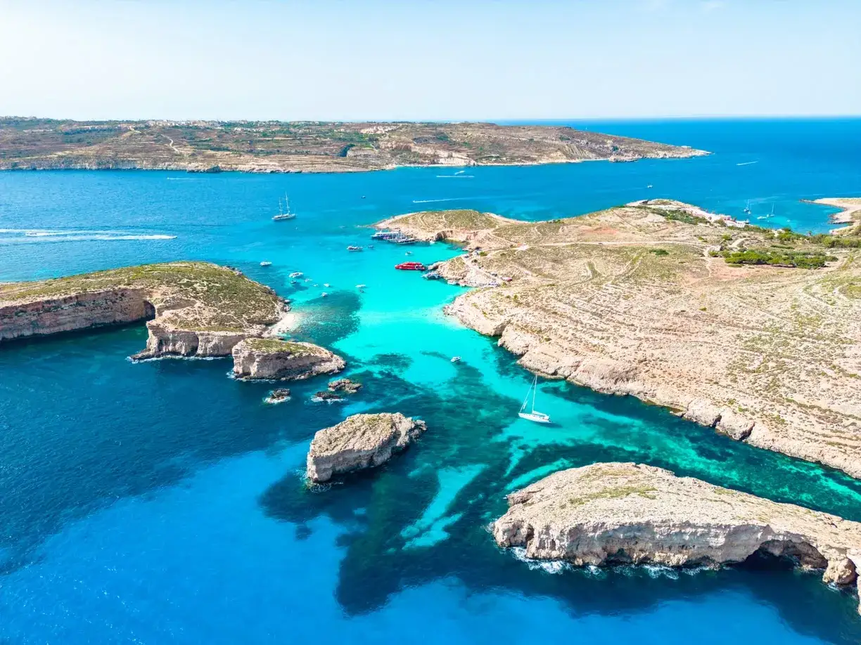 Malta plaże: turkusowa woda, skaliste wybrzeże i łodzie cumujące w zatoce. Rajskie widoki.
