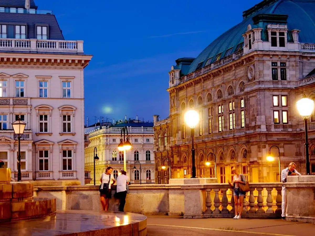 Wieczorny Wiedeń: piękna architektura, iluminowane budynki i ludzie spacerujący po moście. Idealne miejsce, by zobaczyć, co warto w Wiedniu.
