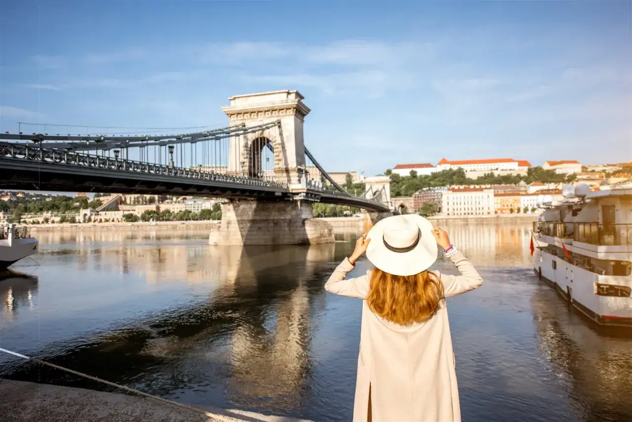 Kobieta w kapeluszu podziwia Most Łańcuchowy w Budapeszcie. Czy na Węgrzech można płacić euro? Nie, walutą jest forint.