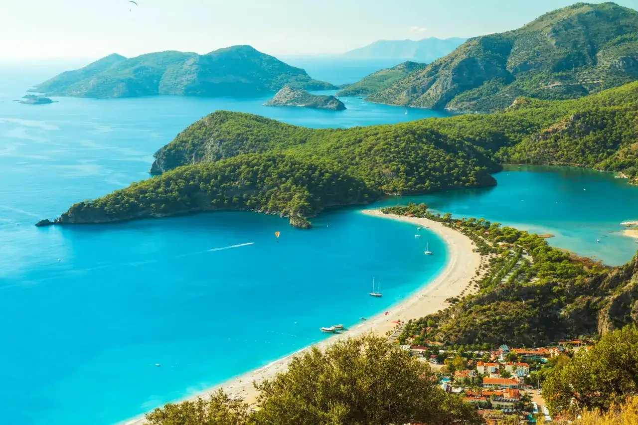 Piękna pogoda w Turcji we wrześniu. Turkusowe morze, zielone wzgórza i piaszczysta plaża w Ölüdeniz. Idealne warunki do paraglidingu.