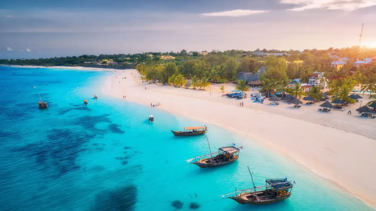 Widok z lotu ptaka na białą plażę i turkusowe morze, gdzie cumują tradycyjne łodzie. Idealne miejsce, kiedy na Zanzibar.