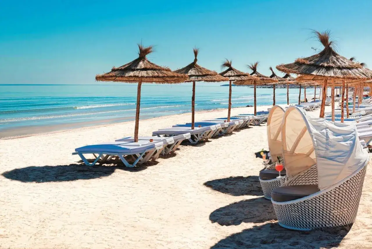 Plaża w Tunezji z rzędami leżaków i parasoli. Atrakcyjne ceny w Tunezji zachęcają do wypoczynku.