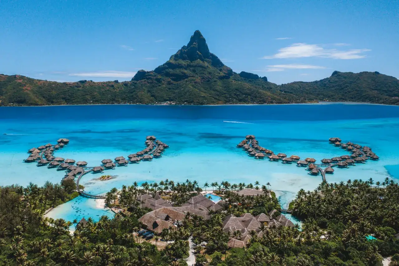 Bora-Bora loty: widok z lotu ptaka na turkusową lagunę, luksusowe bungalowy na wodzie i zielone wzgórza. Rajskie wakacje.