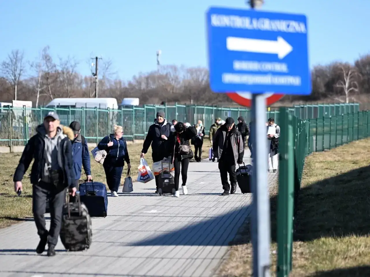 Ludzie z bagażami idą do kontroli granicznej. Warto wiedzieć, jak sprawdzić numer paszportu ukraińskiego przed podróżą.