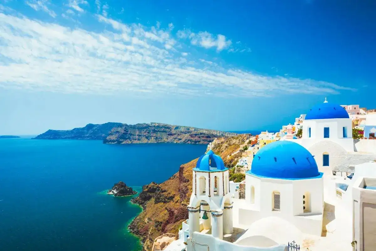 Santorini w październiku: błękitne kopuły kościołów na tle morza i skalistych klifów. Idealna pogoda w Grecji.