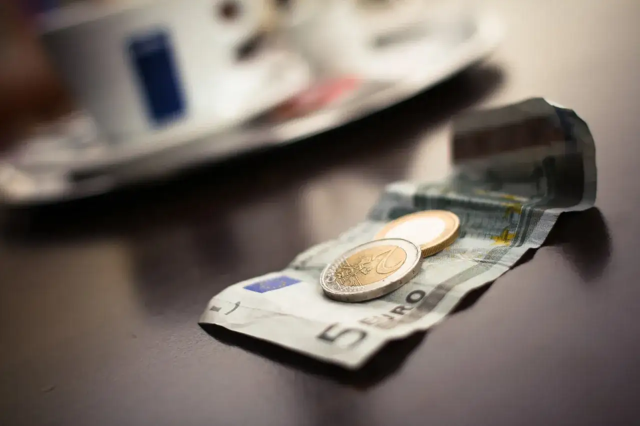 Na stole leży banknot 5 euro i monety. To waluta w Grecji, idealna na kawę.