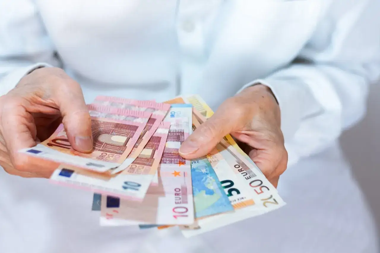 Dłonie trzymające plik banknotów euro. Czy w Czechach można płacić euro? Tak, euro jest akceptowane w wielu miejscach.