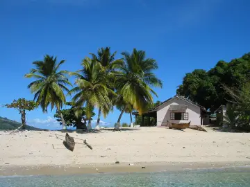 Rajska plaża z palmami, łodzią i domkiem. Zastanawiasz się, ile się leci na Madagaskar?
